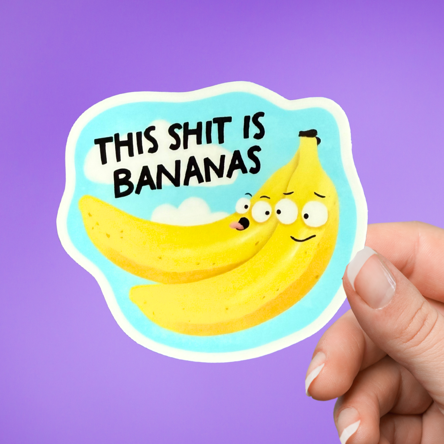 Sticker with cartoon bananas and text 'THIS SHIT IS BANANAS' held by a hand against a purple background